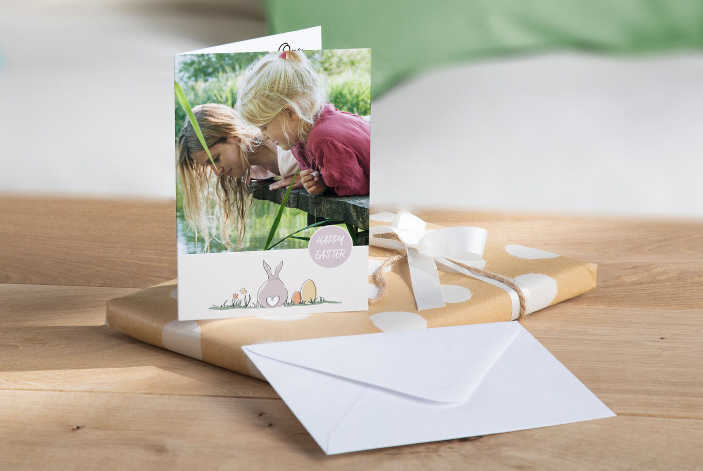 Two children look into an envelope surrounded by gift wrapping and Easter decorations.