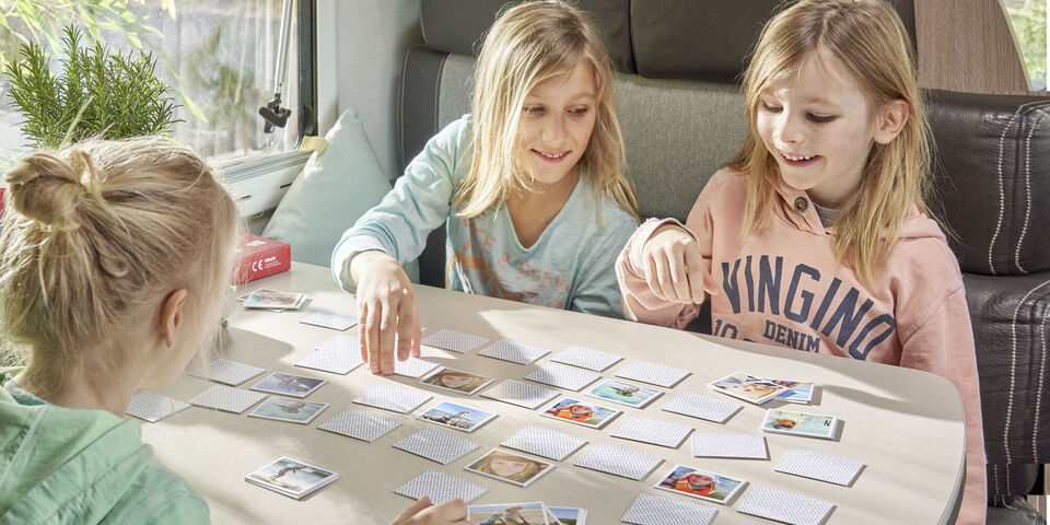 Three children play a memory game at the table