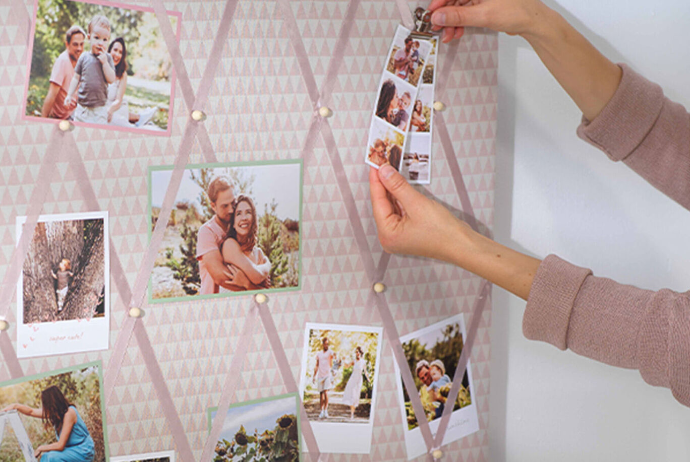Person hangs photo cards on a wall collage with personal memories