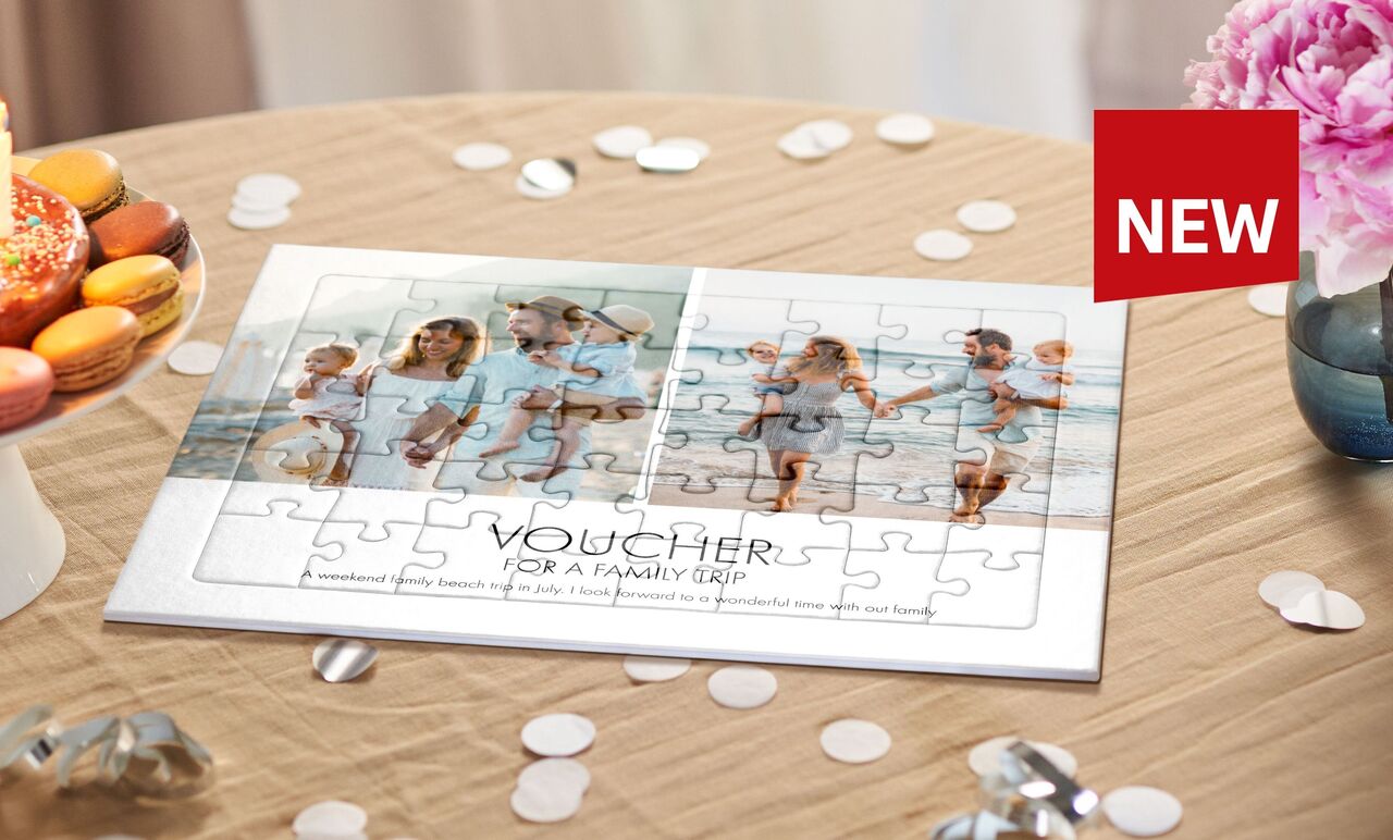 A personalized puzzle on a table with delicious sweets. The puzzle shows a family at the beach with the text 'VOUCHER FOR A FAMILY TRIP'.