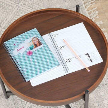 A table with a colorful notebook and an open calendar. A pencil is ready.