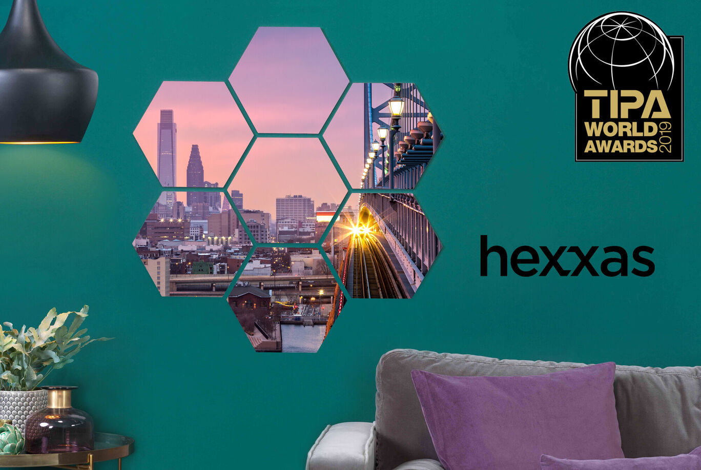A modern wall art piece with photorealistic hexagons showing city views. It includes golden light rays and the TIPA World Awards logo.