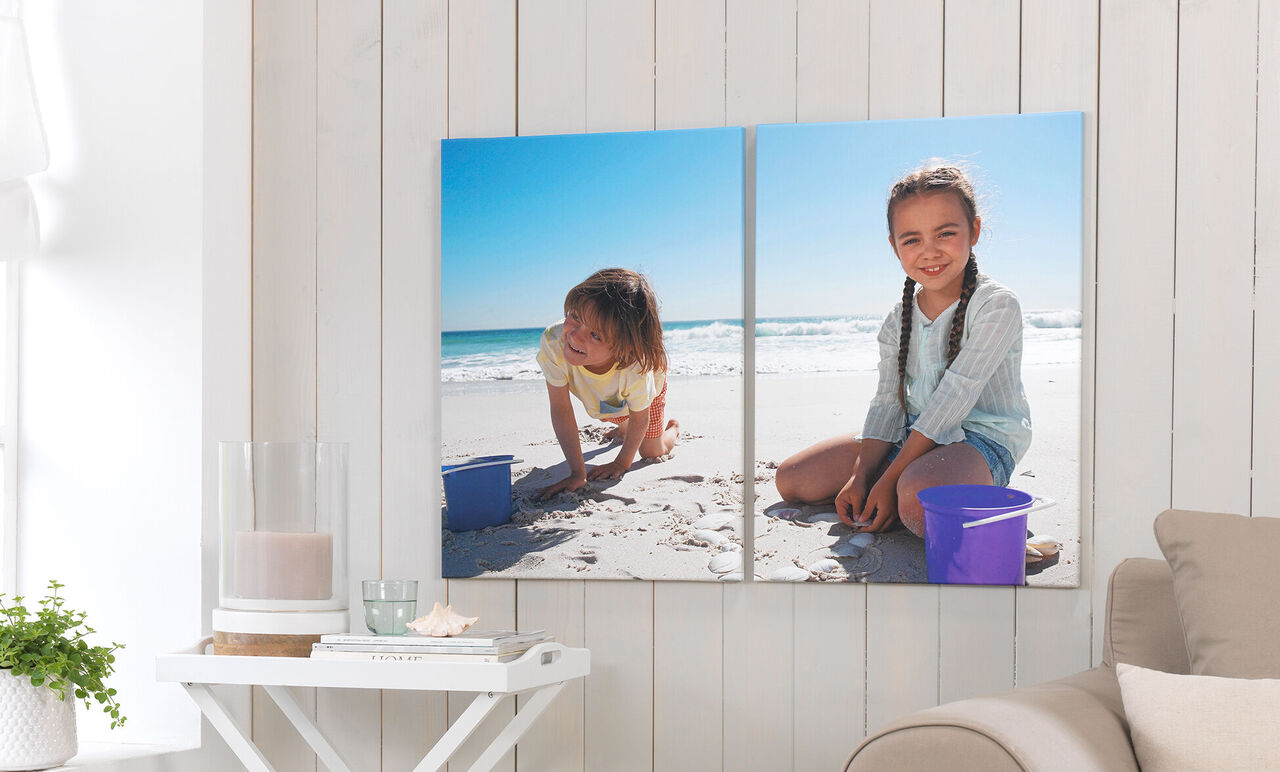 Two children play on the beach with sand and buckets