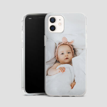 A phone with a cute baby in bed, snuggled in a blanket.