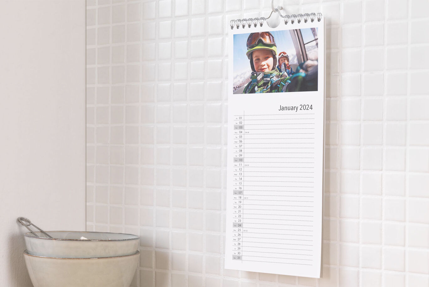 A wall calendar for January 2024 on a wall, with a photo and space for notes.