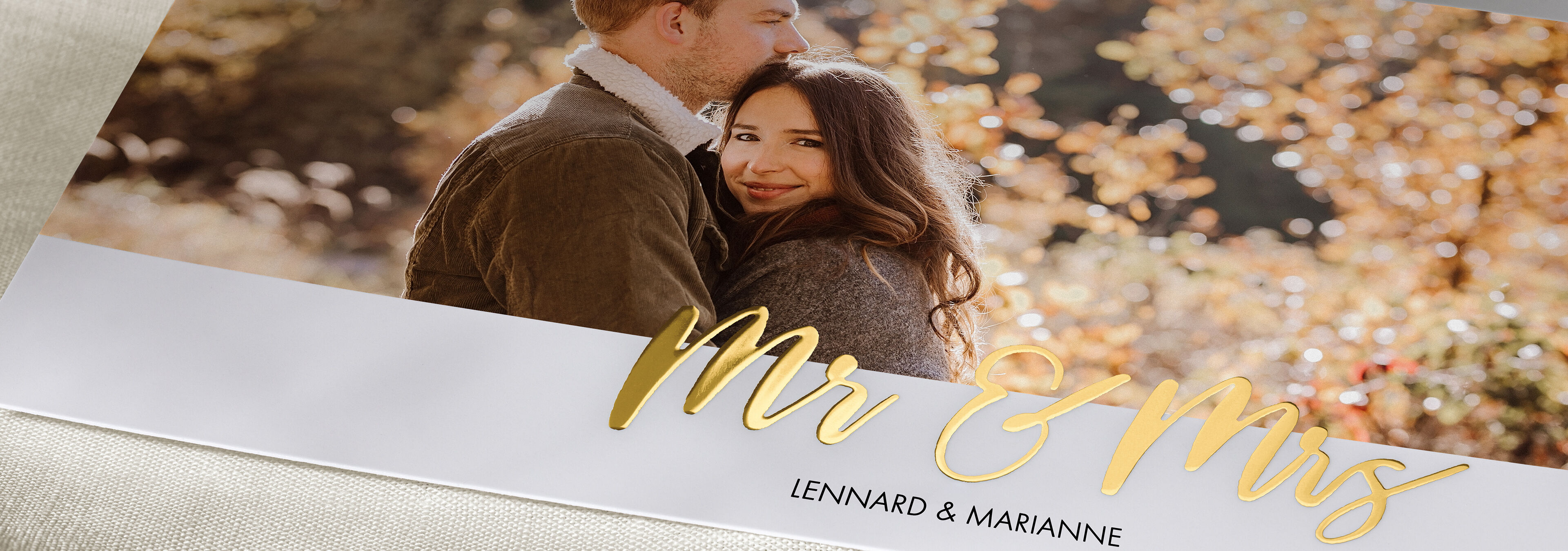 A happy couple sitting in nature, surrounded by autumn colors. The phrase "Mr & Mrs" elegantly displayed in the image.