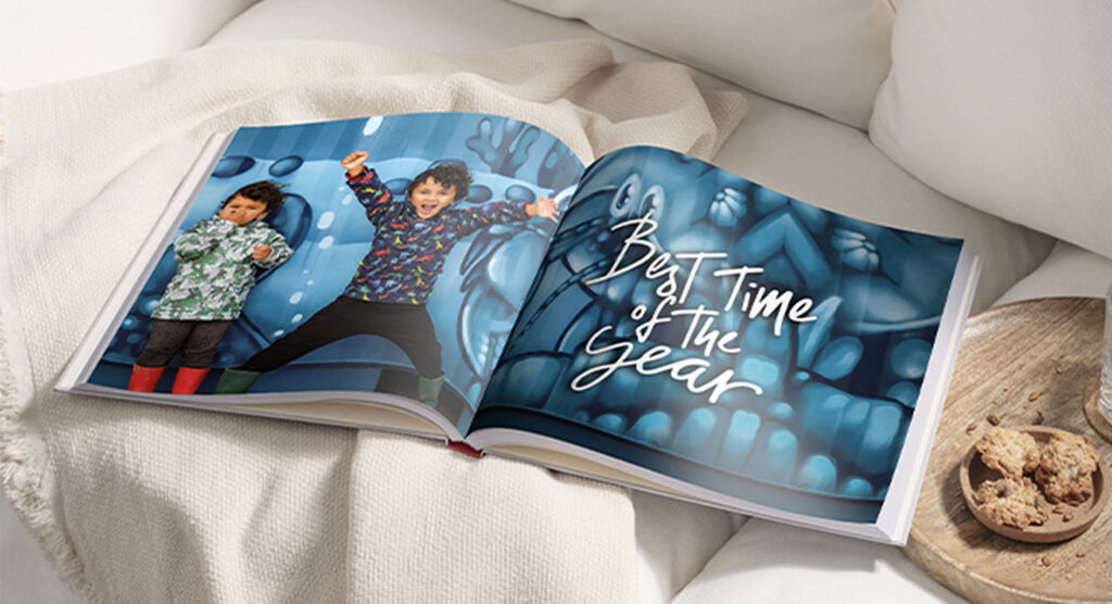 An opened photo book with children having fun, surrounded by colorful illustrations.