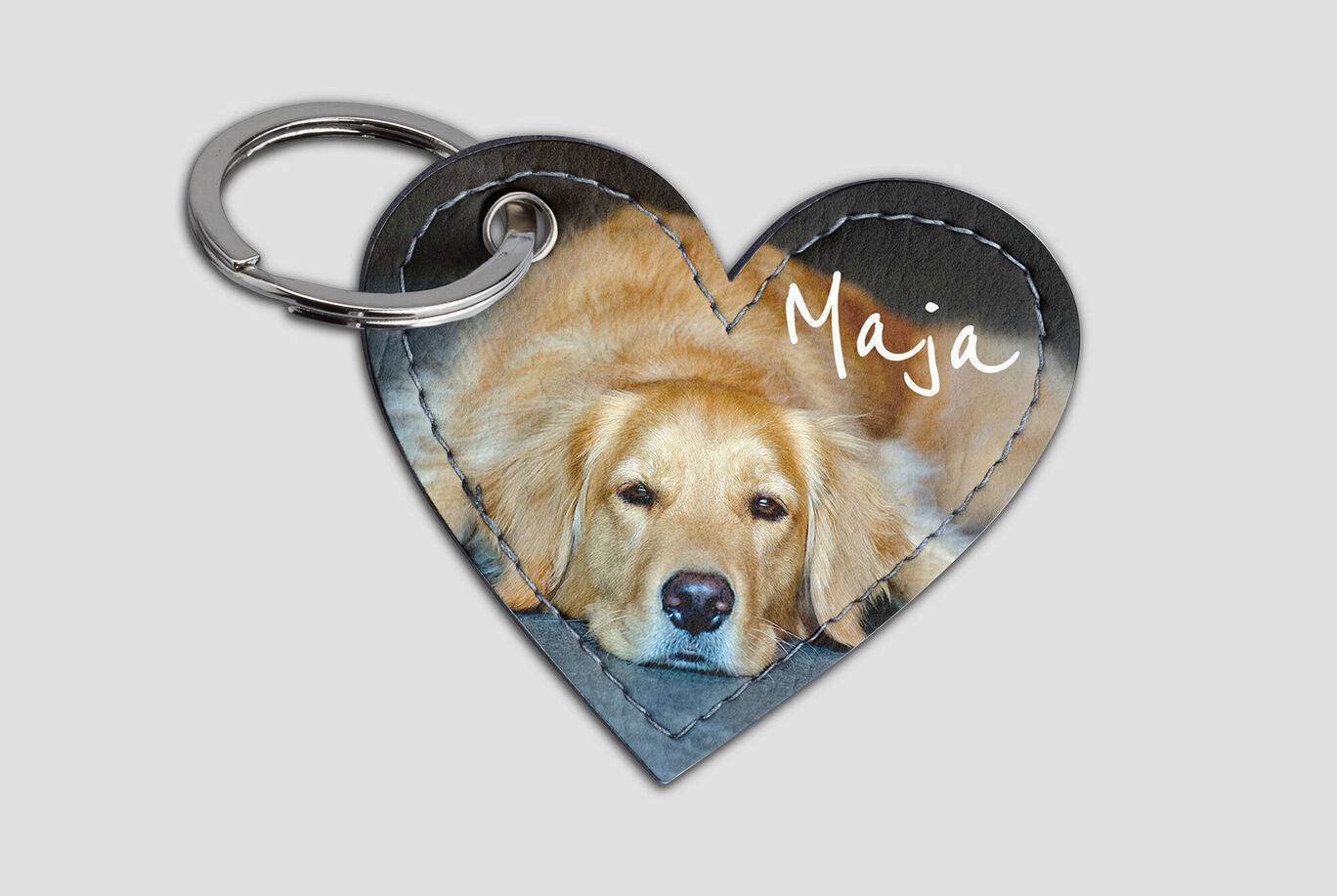 A heart-shaped keychain with an image of a Golden Retriever named Maja, relaxing.