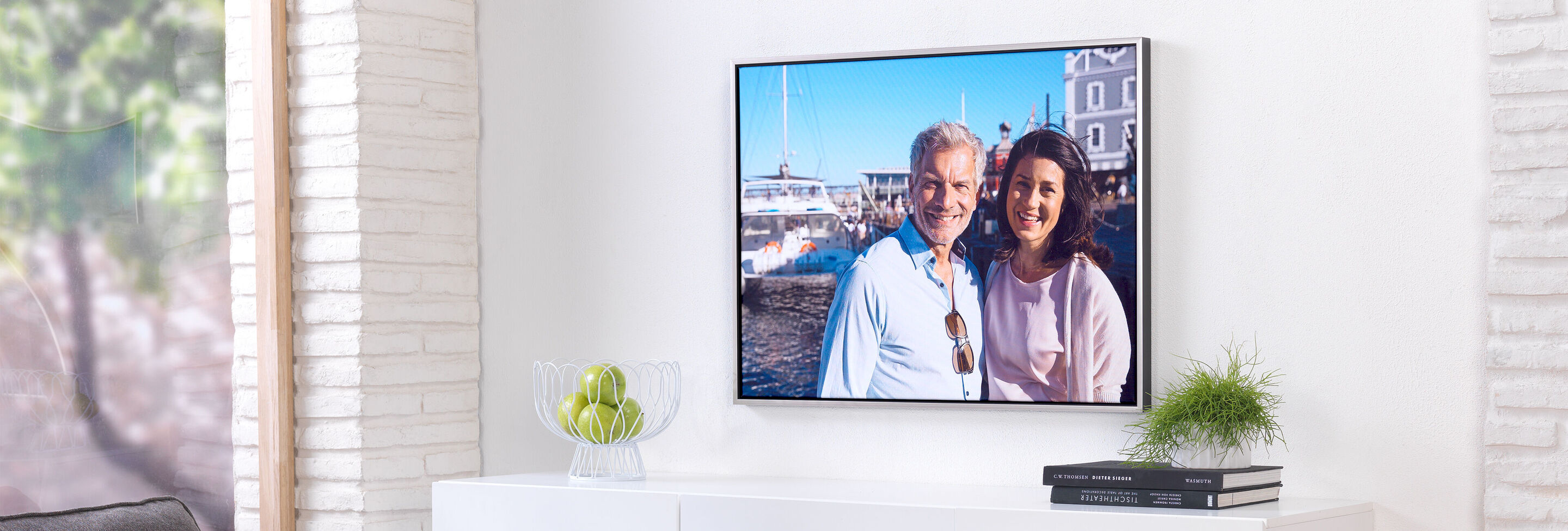 A couple smiling happily in front of a harbor with boats in the background.