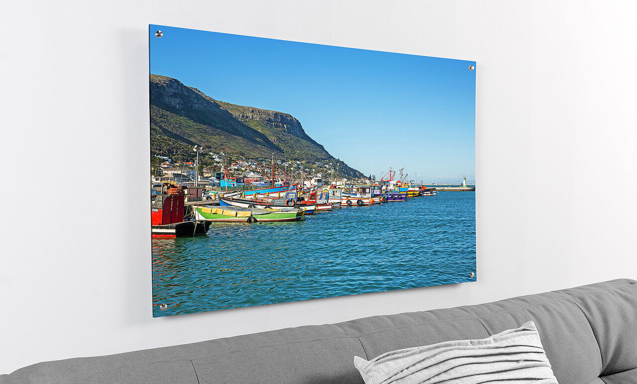 Colorful boats in the harbor of a calm body of water with mountains in the background.