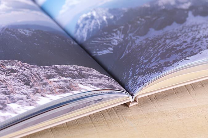 Two pages of an open photo book with landscape images of mountains and nature.