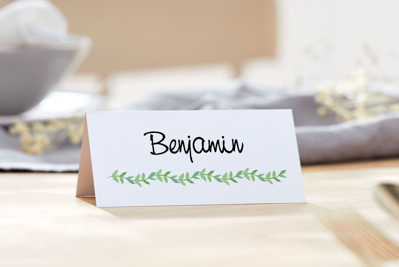 A table with a small name card for a guest named Benjamin, decorated with green leaves.