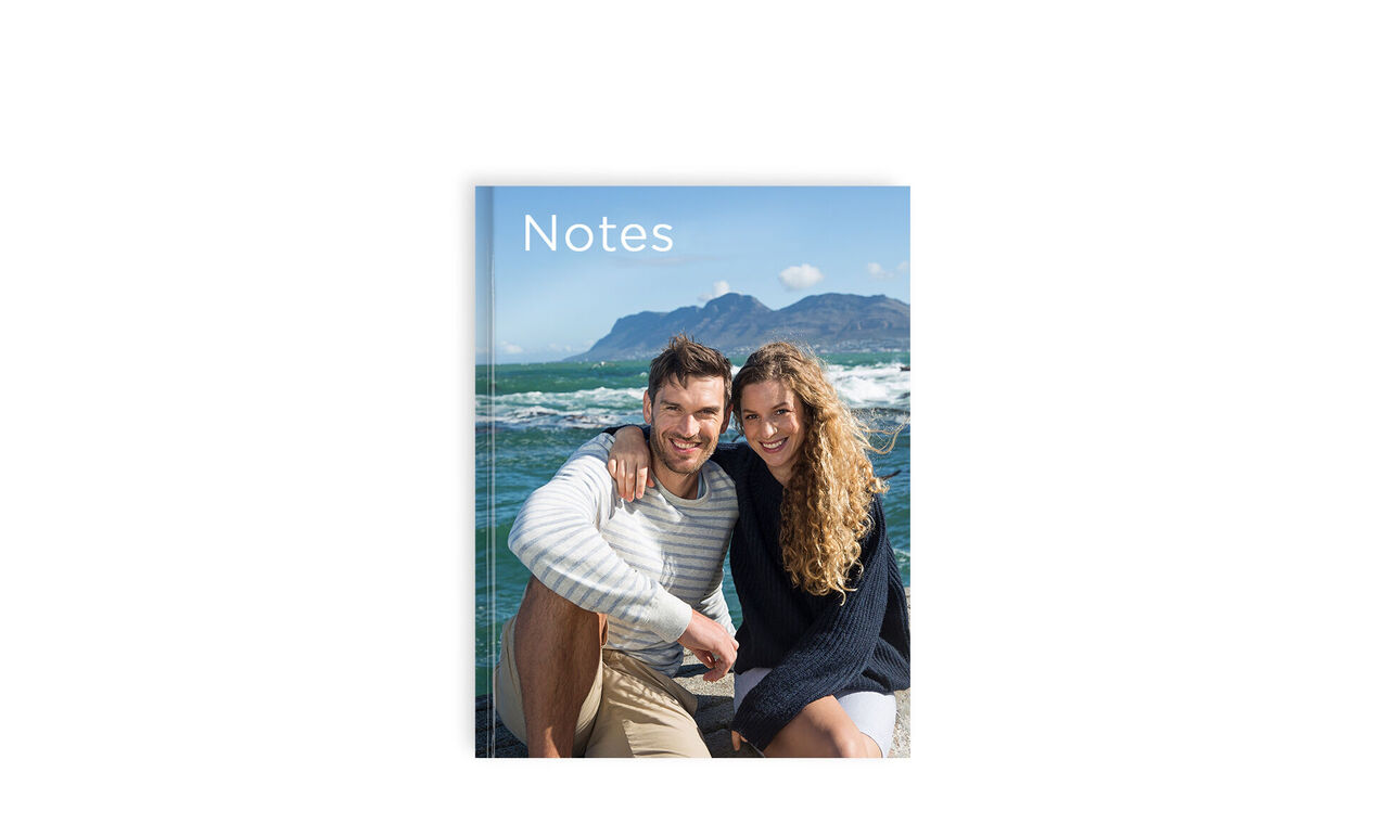 A couple sits on the beach holding a notebook titled 'Notes'.