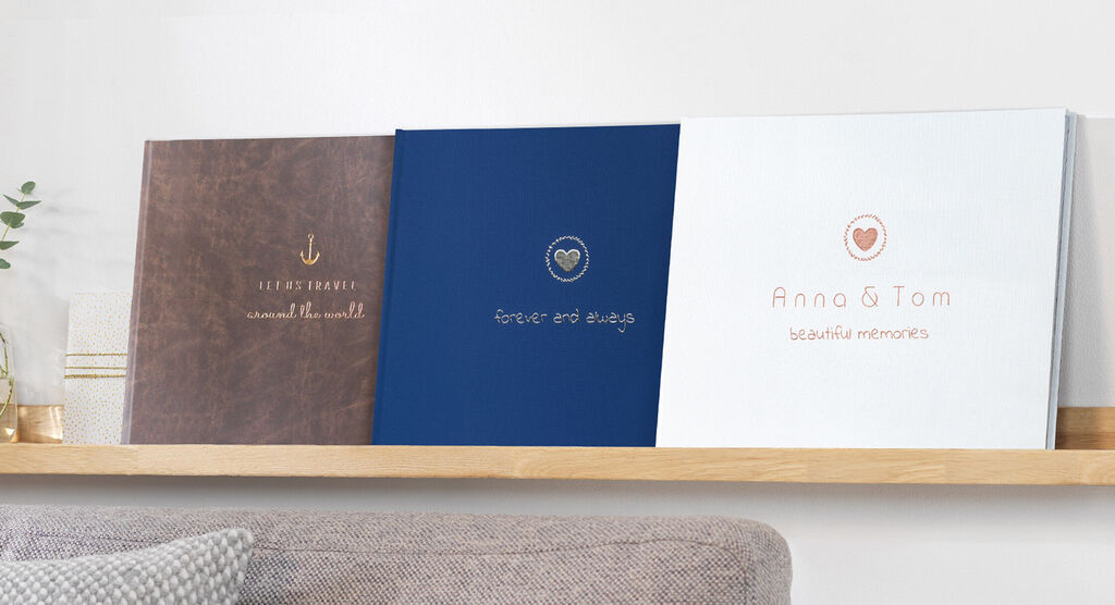 Three attractively designed CEWE photo books on a shelf showing different designs.