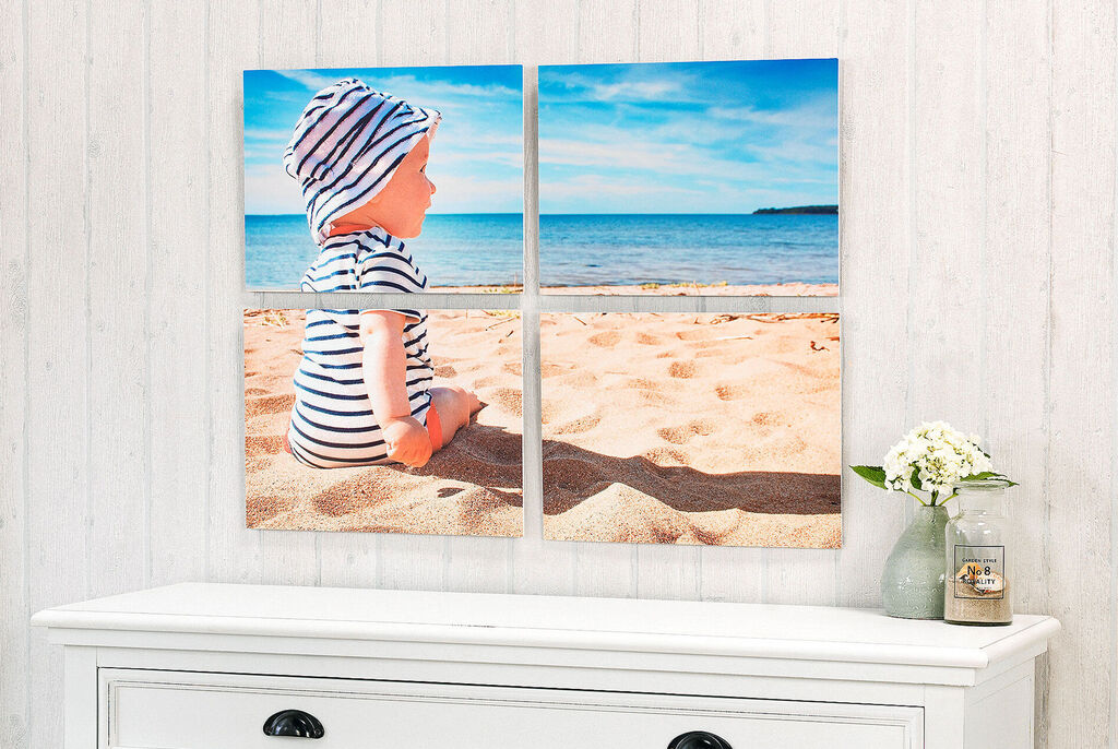 A small child in a striped shirt sitting on the beach looking at the water