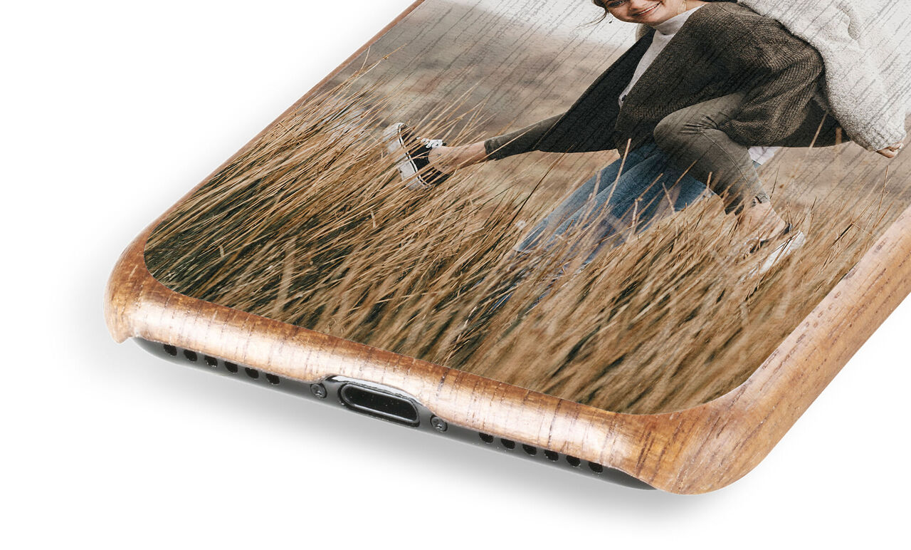 Detail view of a wooden phone case with a picture of a happy couple in a field