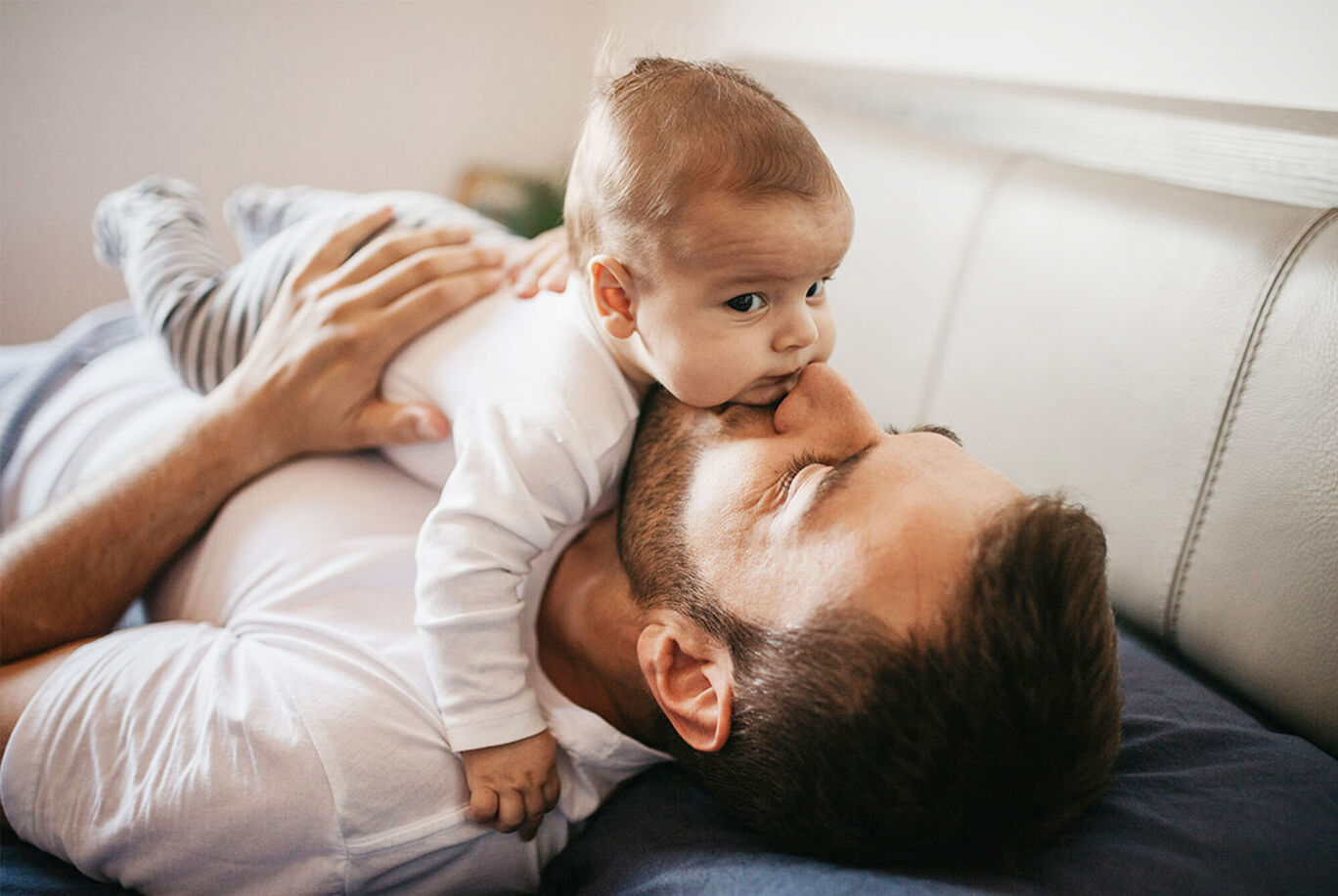 Father lovingly playing with his baby on the bed.