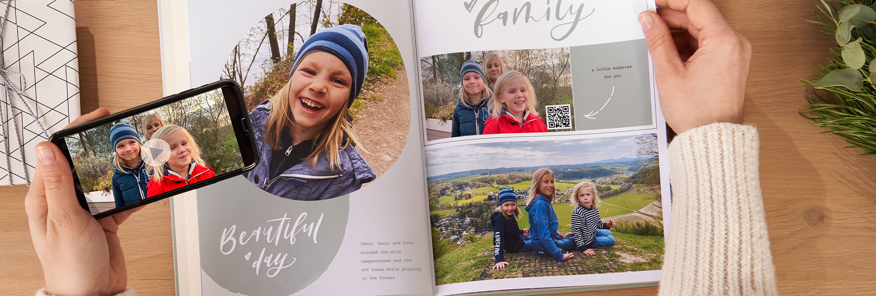 A person looks at a photo book with family memories and a smartphone displaying a snapshot.