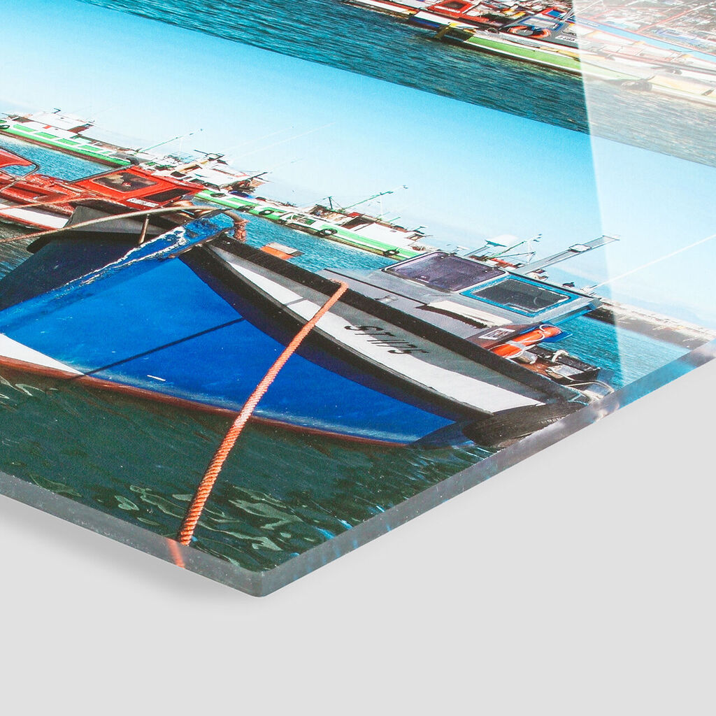 A colorful boat gently rocks on the water in a harbor with many boats in the background.