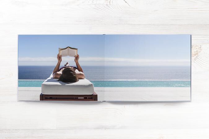 A person relaxes by the pool and reads a book.
