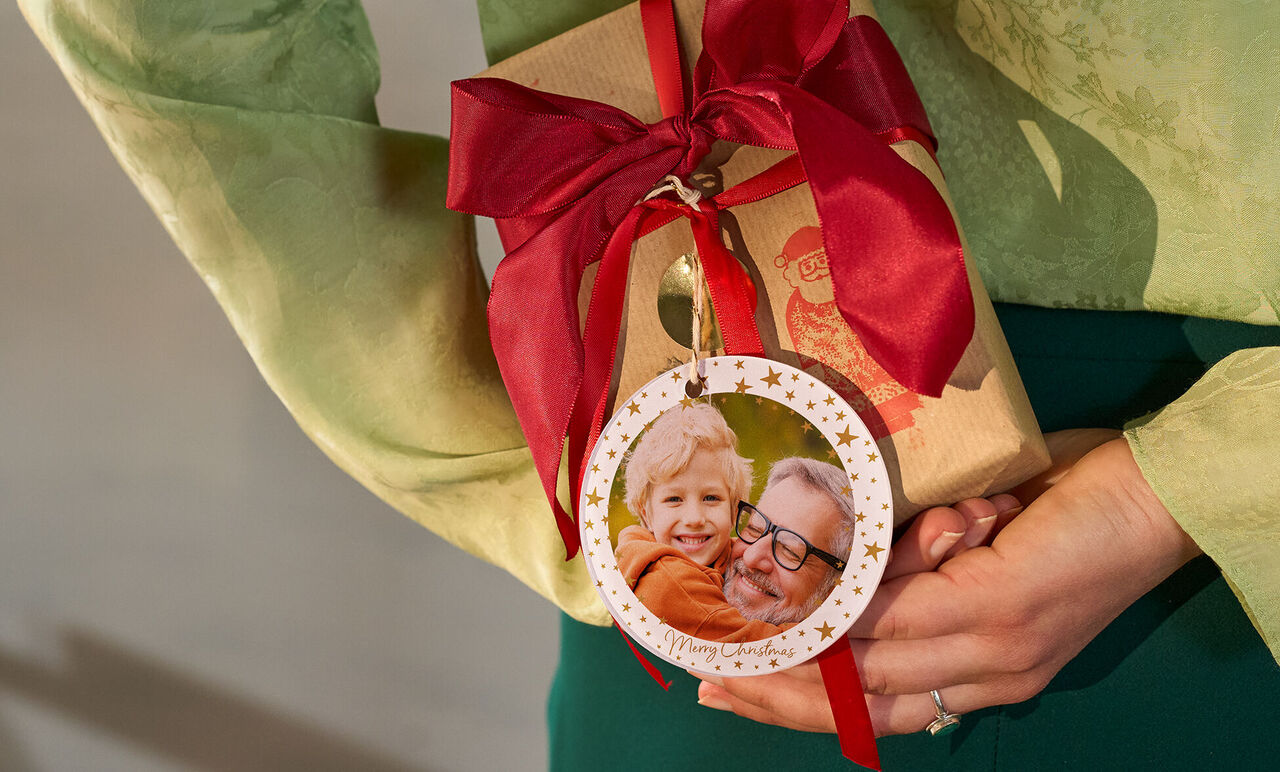 A person holds a lovingly wrapped gift with a red ribbon.
