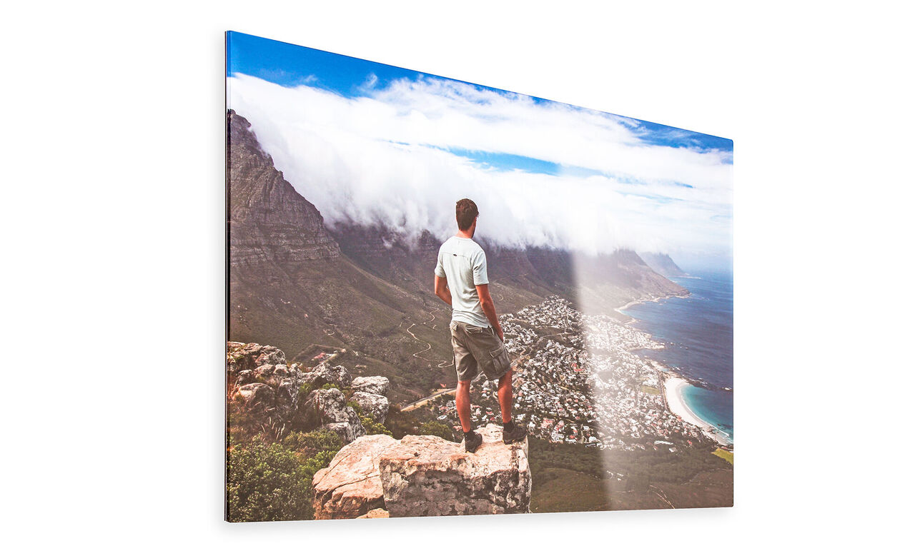 A man stands on a rock overlooking the coast and city.