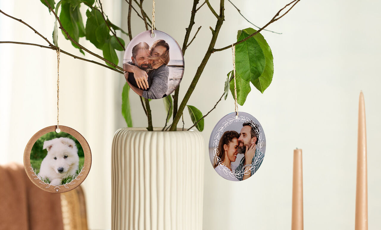 Three round pictures hanging on a decorative branch in a vase.