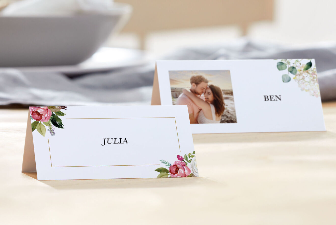 Two place cards with the names Julia and Ben, surrounded by blooming flowers and a photo.
