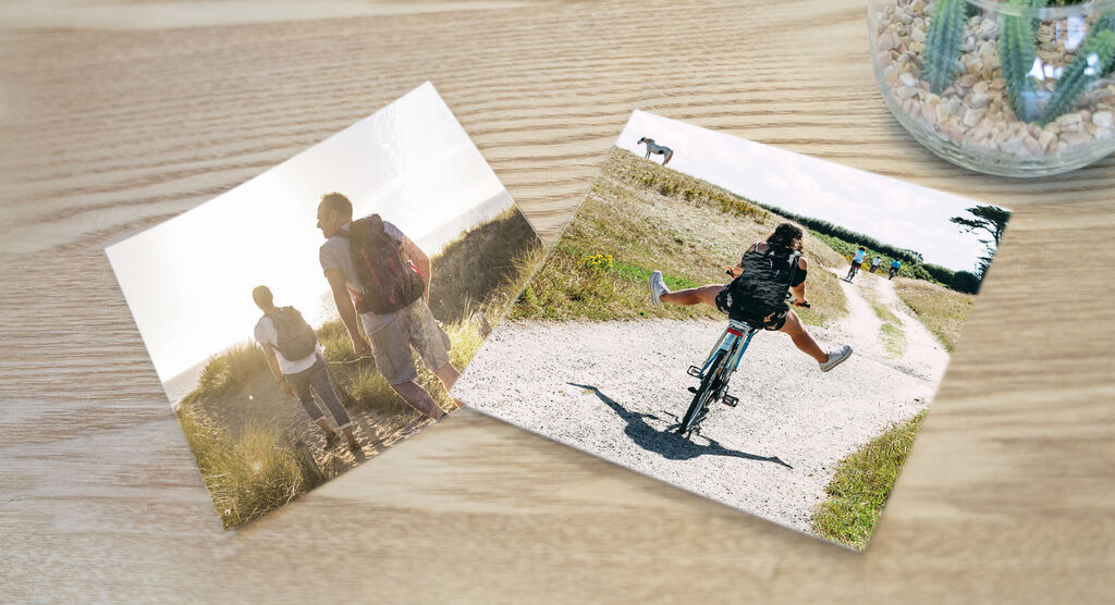 Two photos on a wooden table. Left: wandering people in sunlight. Right: a boy on a bike. Both show nature moments.