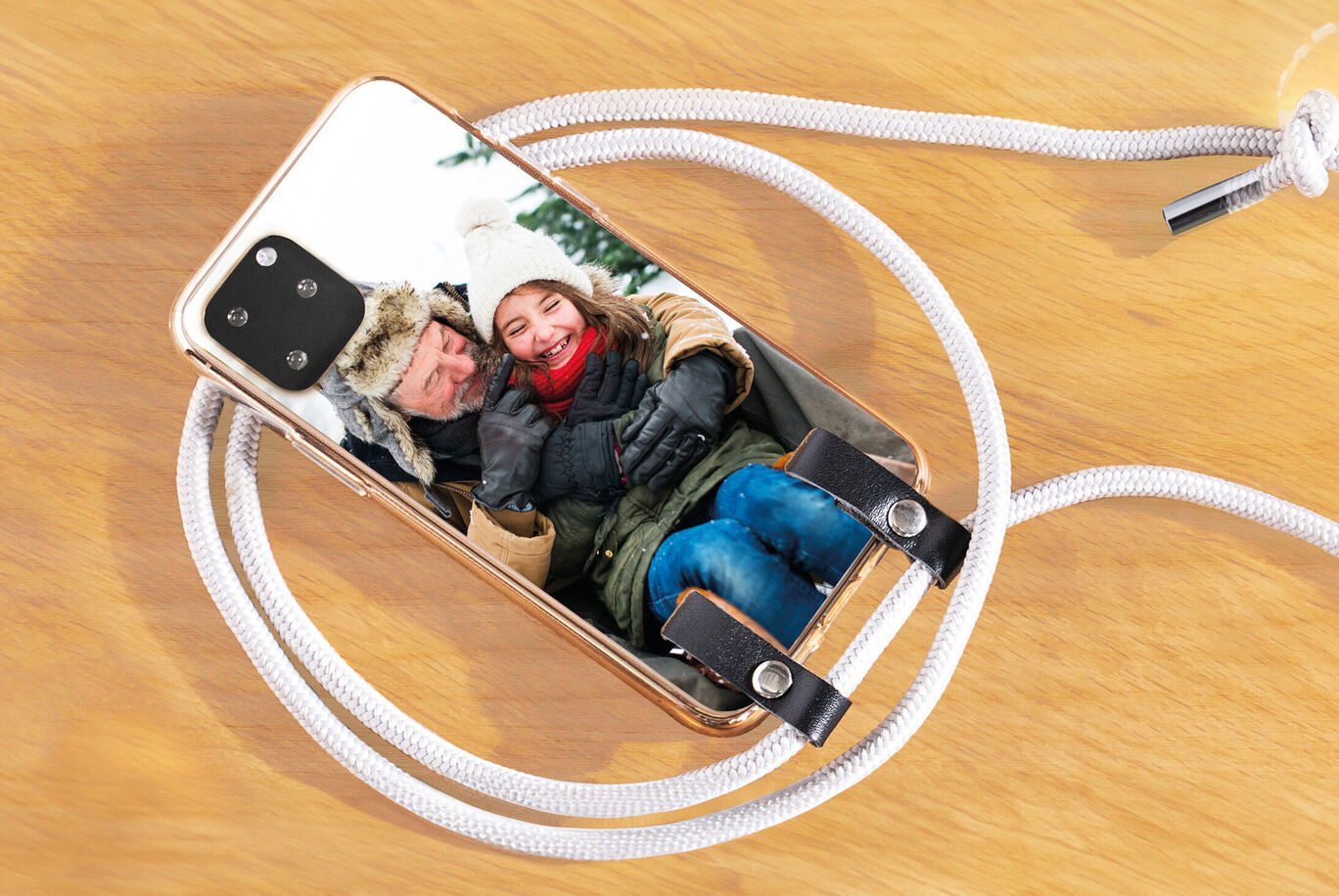A smartphone lies on a wooden table showing an image of a happy moment outdoors.