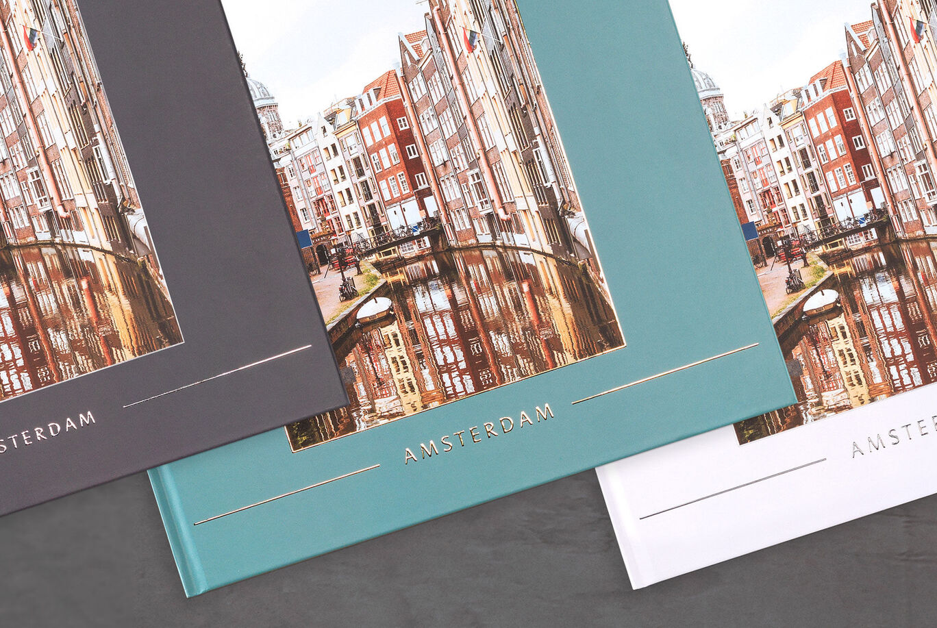 Three different CEWE photo book covers in bright colors with the city of Amsterdam in the background.