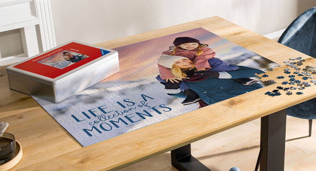 A puzzle with the inscription 'Life is a collection of moments', on a table with toys and a red box.