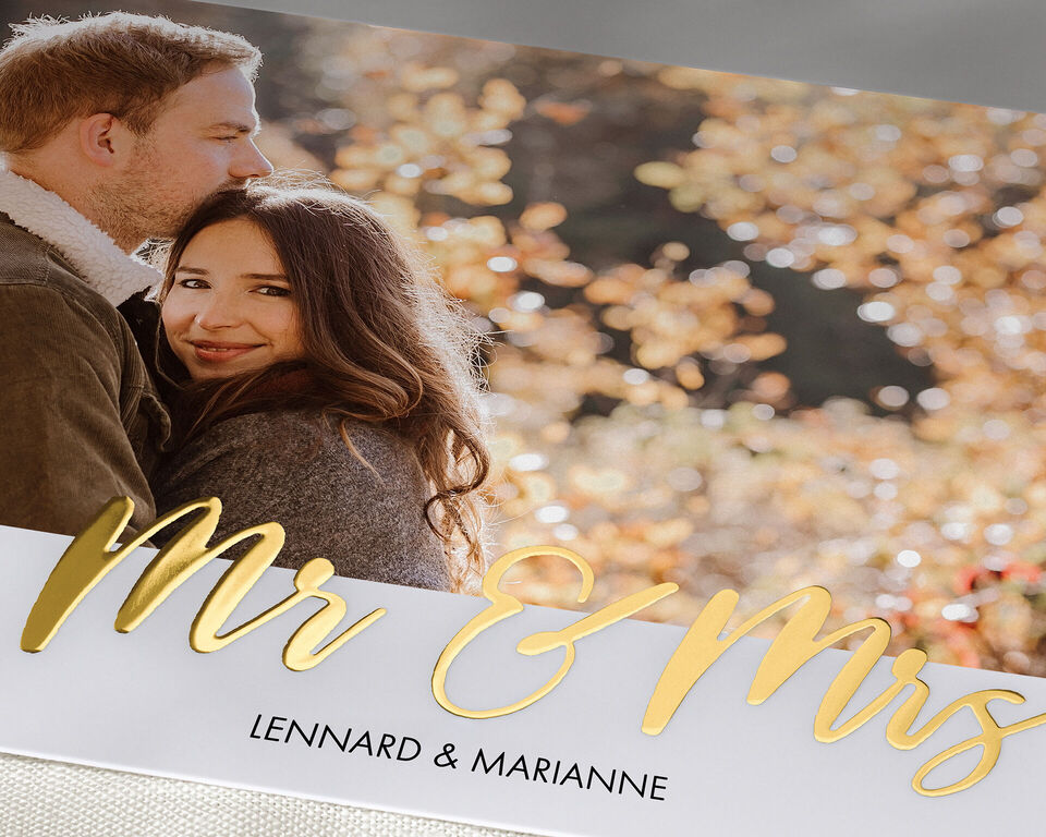A couple stands in an autumn park, surrounded by colorful leaves. They enjoy a romantic moment.