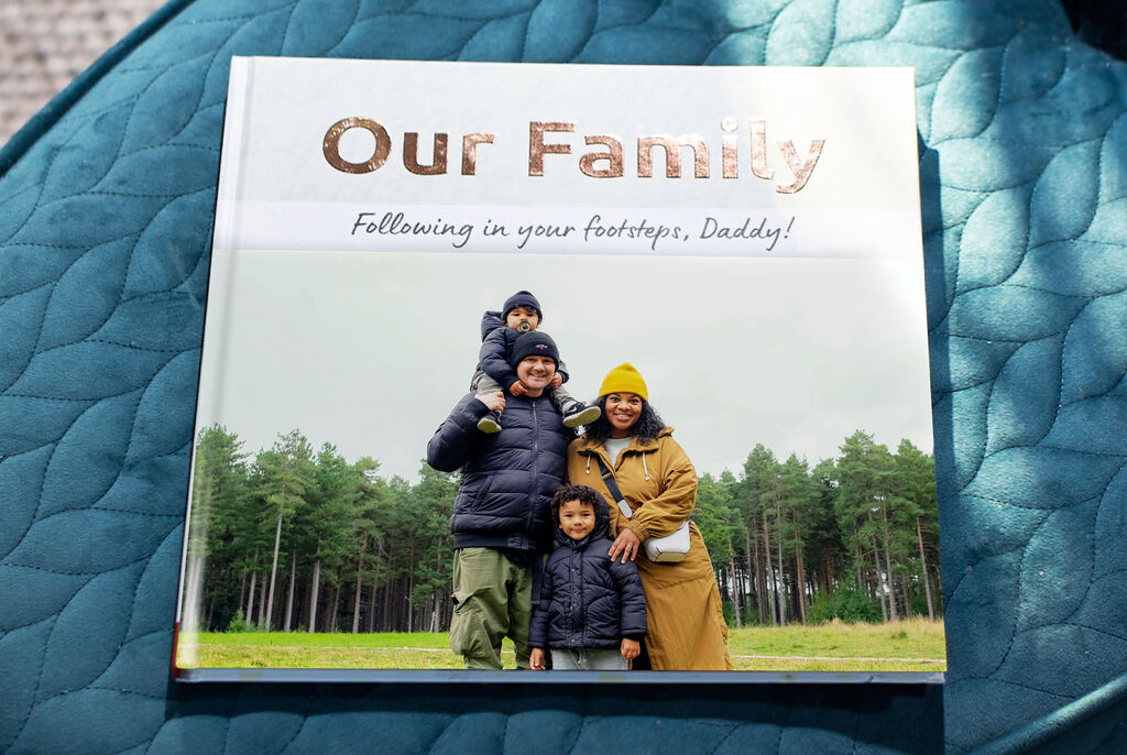 Family poses happily outdoors with a CEWE PHOTO BOOK.