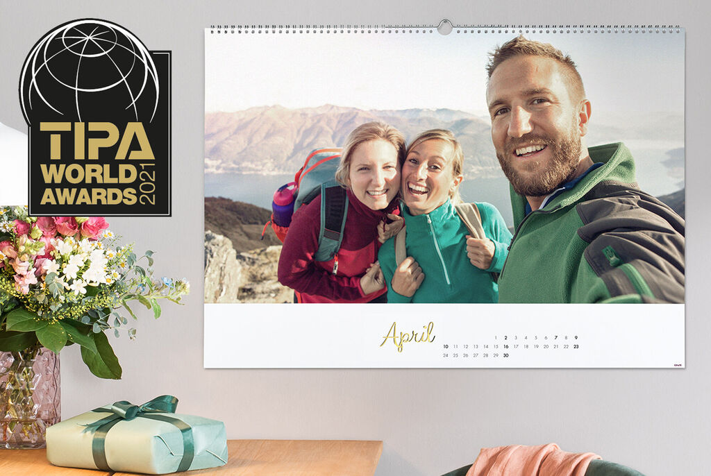 A cheerful family photo in front of a mountain landscape in a CEWE photo calendar for April.