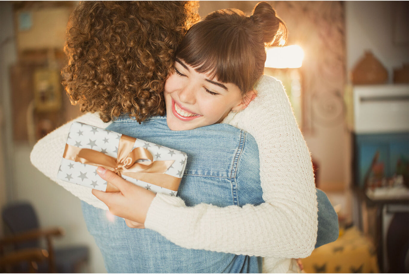 Two people hug each other warmly and hold a beautifully wrapped gift.