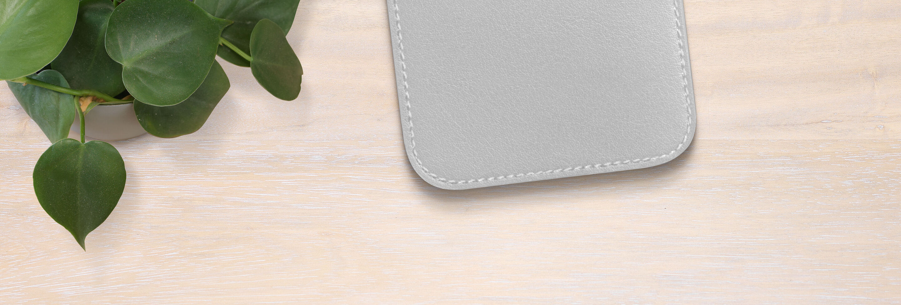 A gray square mat lies on a light table next to a plant.