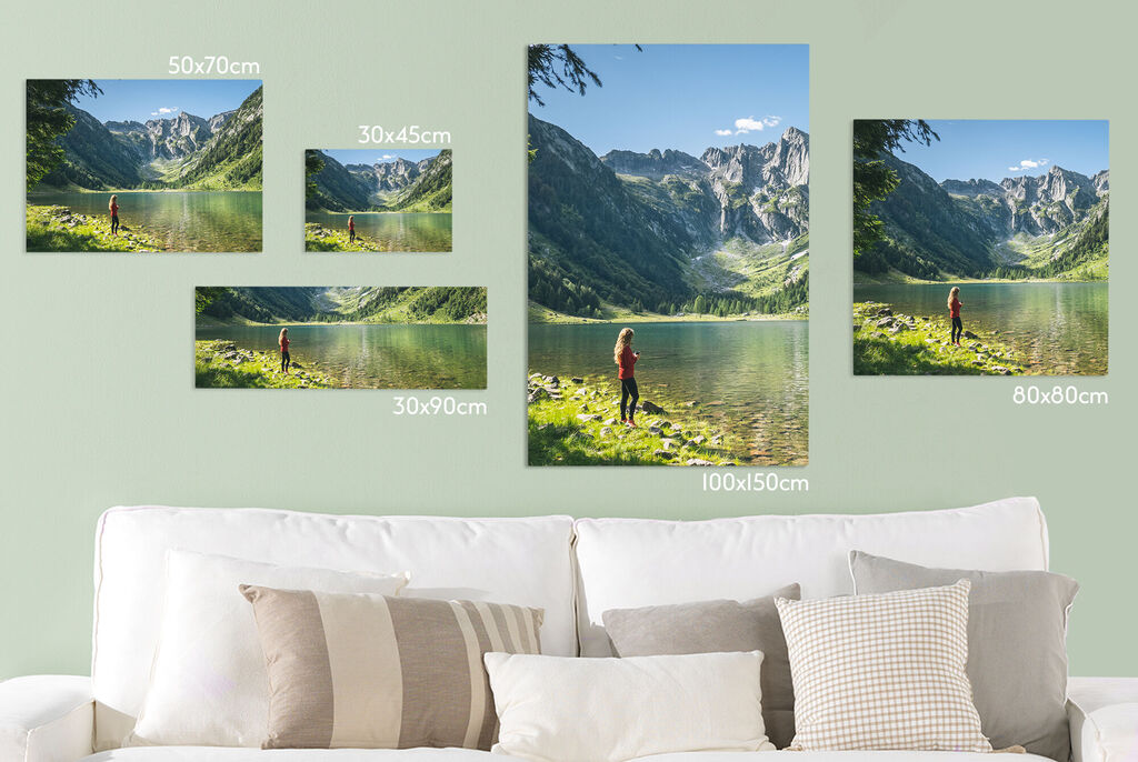 Various wall images of a lake with mountains in the background, framed by a cozy couch.