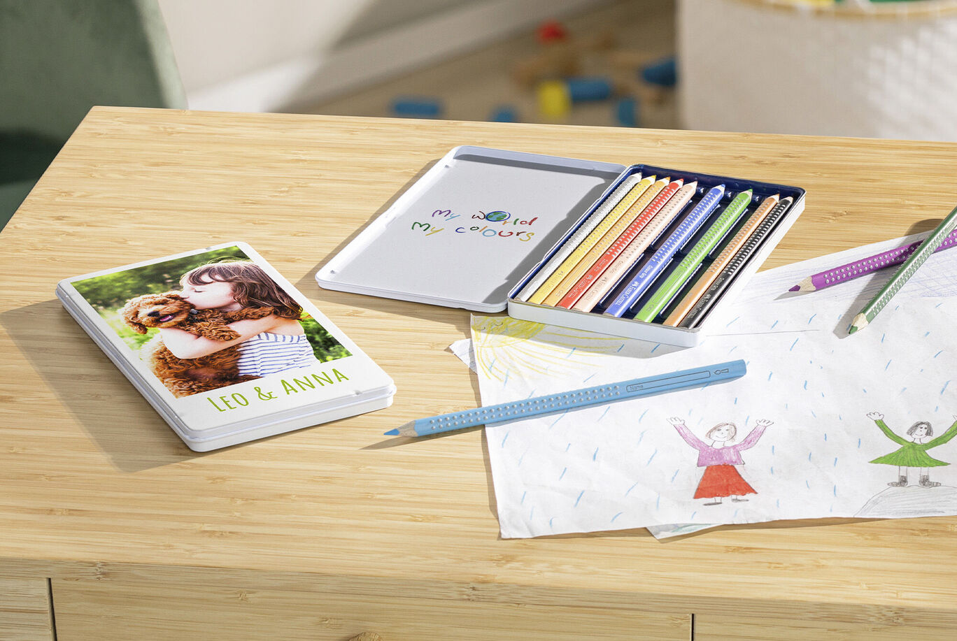A lovingly designed CEWE photo book lies on a table, next to colored pencils and children's drawings. It shows a happy memory of Leo and Anna with a dog.