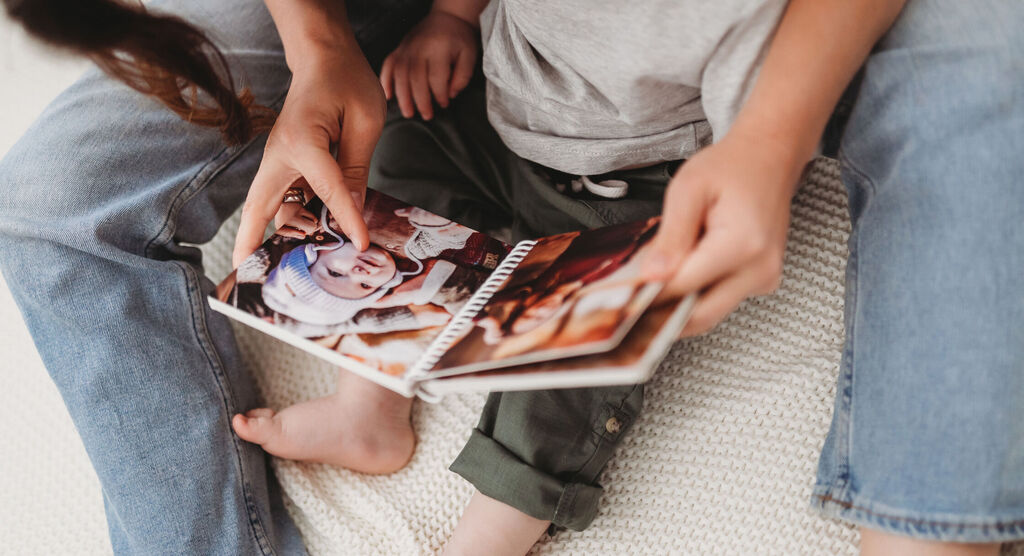 A child looks at a photo book full of memories with an adult.
