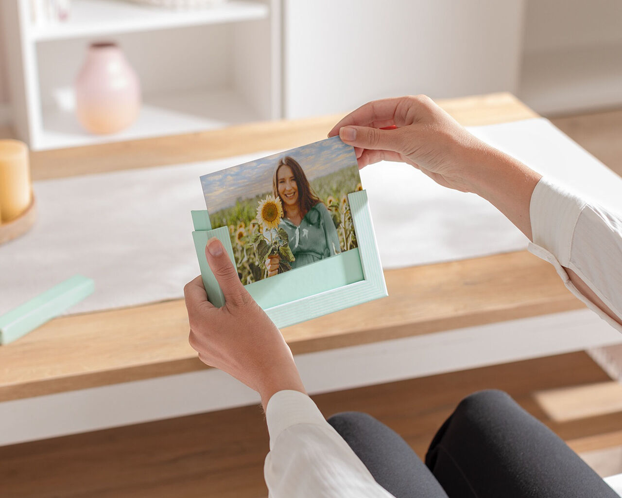 A person holds a photo with sunflowers in a mint green box.