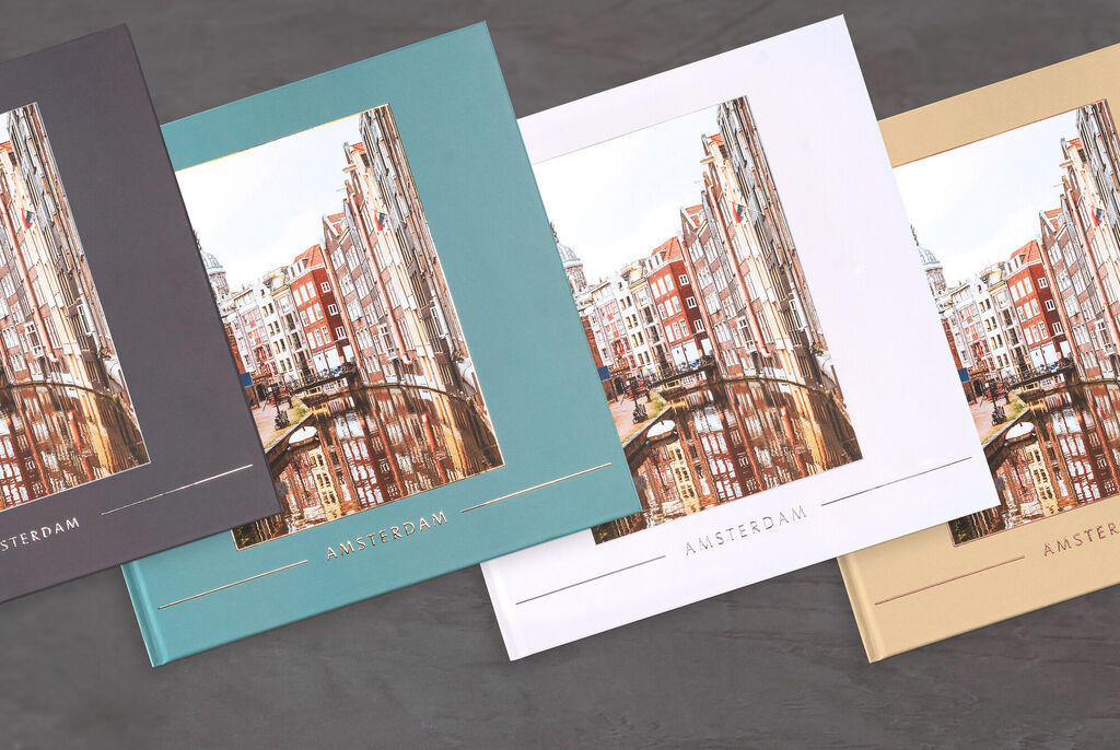 Three different colors of CEWE photo books titled 'Amsterdam', elegantly arranged.