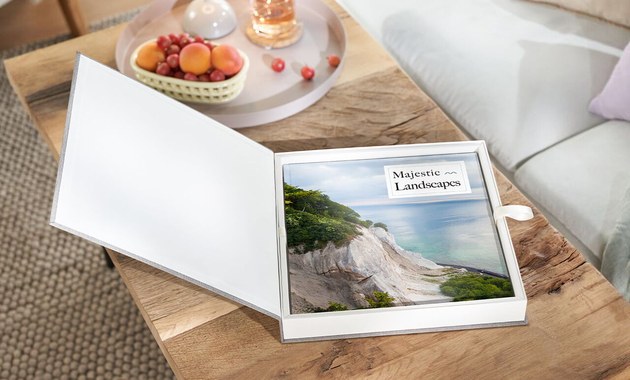 An opened photo book titled 'Majestic Landscapes' on a table. The background shows a cozy living atmosphere.