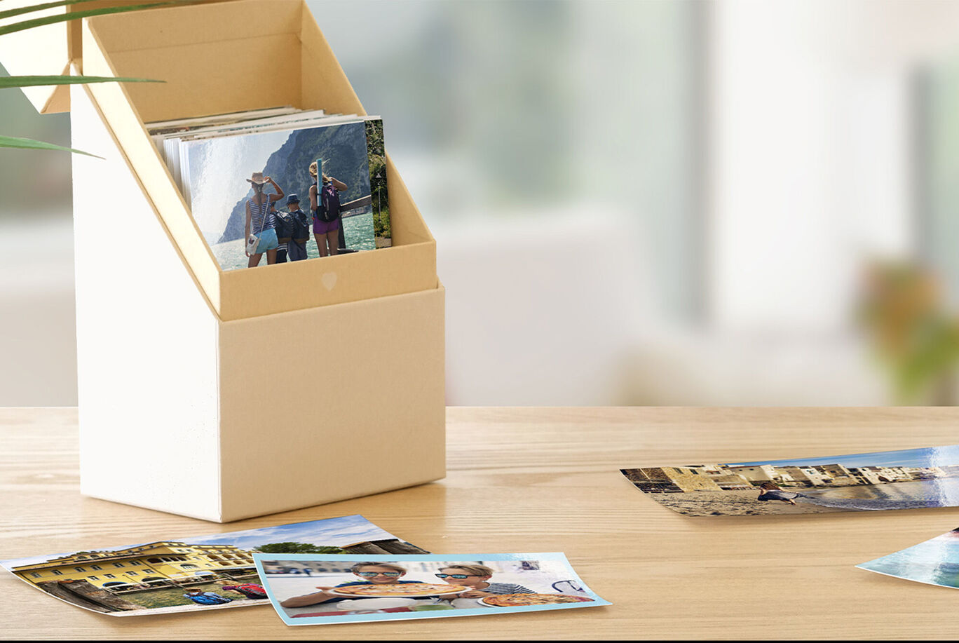 A decorative box with photos and some images lying in the foreground on a table.
