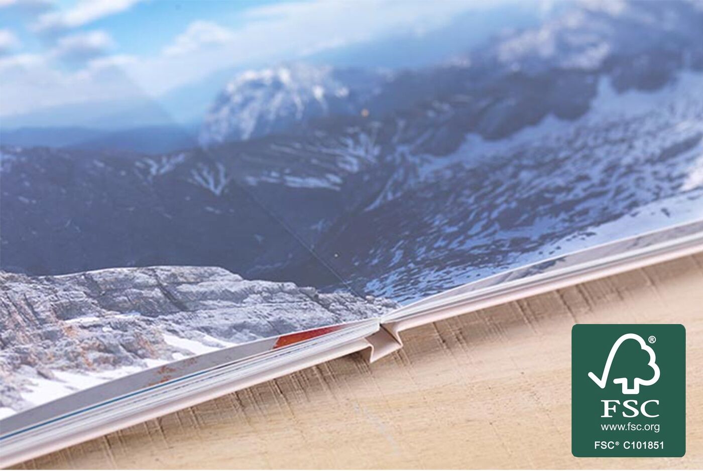 Open page of a photo book featuring mountain landscapes and FSC logo.