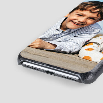 A happy person relaxes on a couch with a phone.