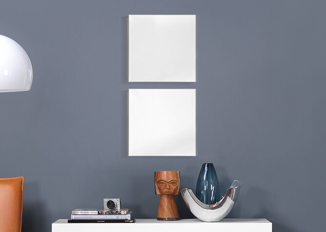 Two empty white frames on a gray wall above a table with decorative objects.