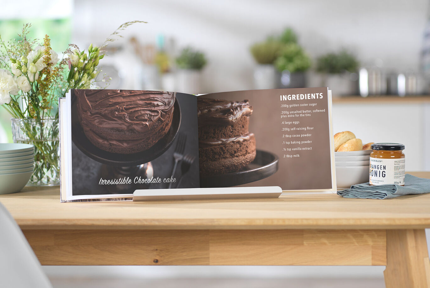 An open recipe book shows a tempting chocolate cake with ingredients.