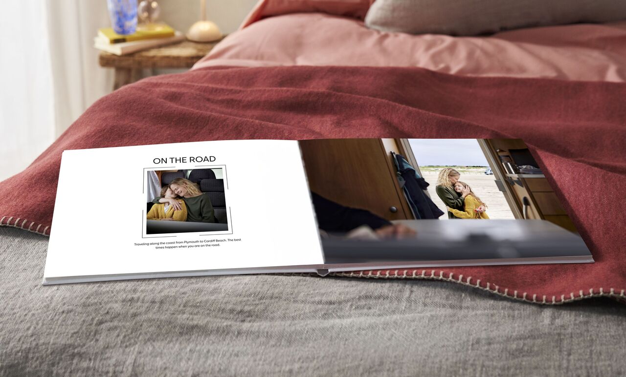 An open photo book on a bed. One page shows a picture of a person in a car looking thoughtfully.