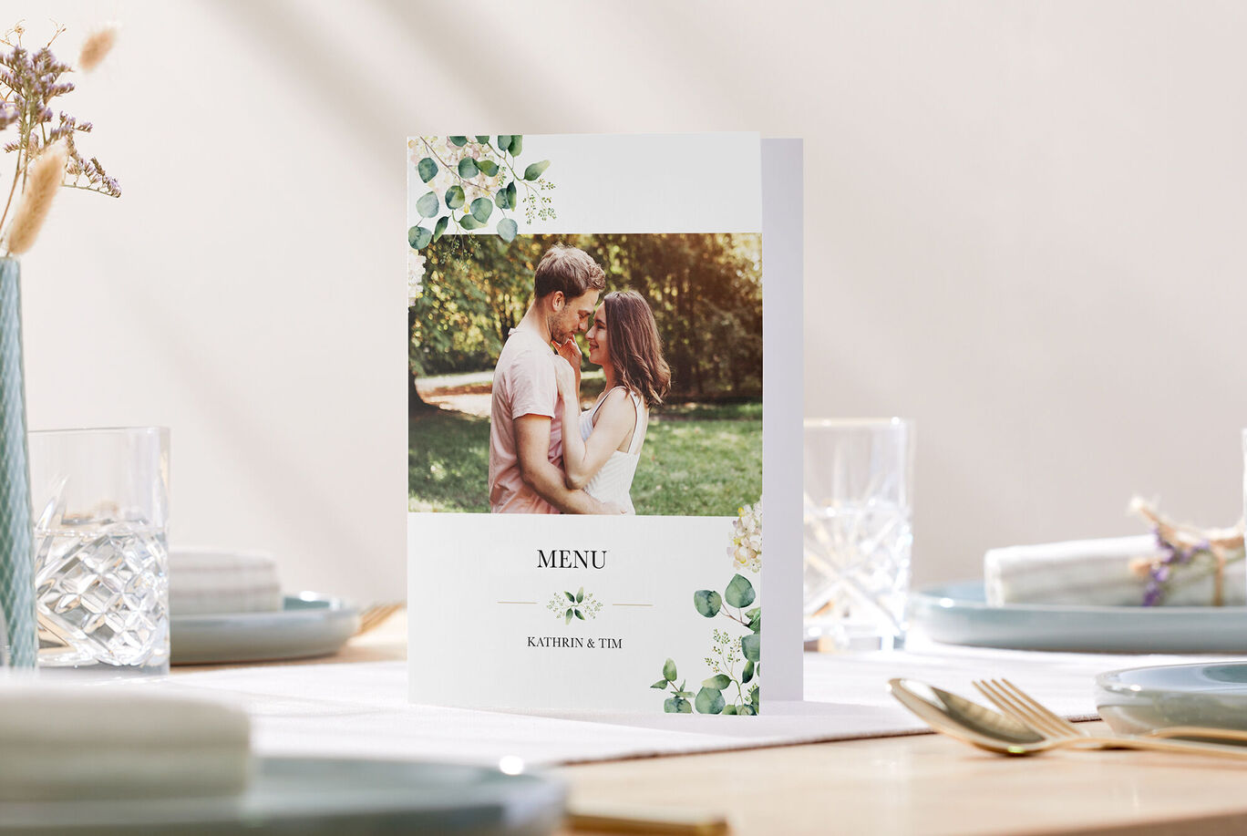 A loving menu card with a couple in a green garden background, surrounded by floral vines and elegant china.